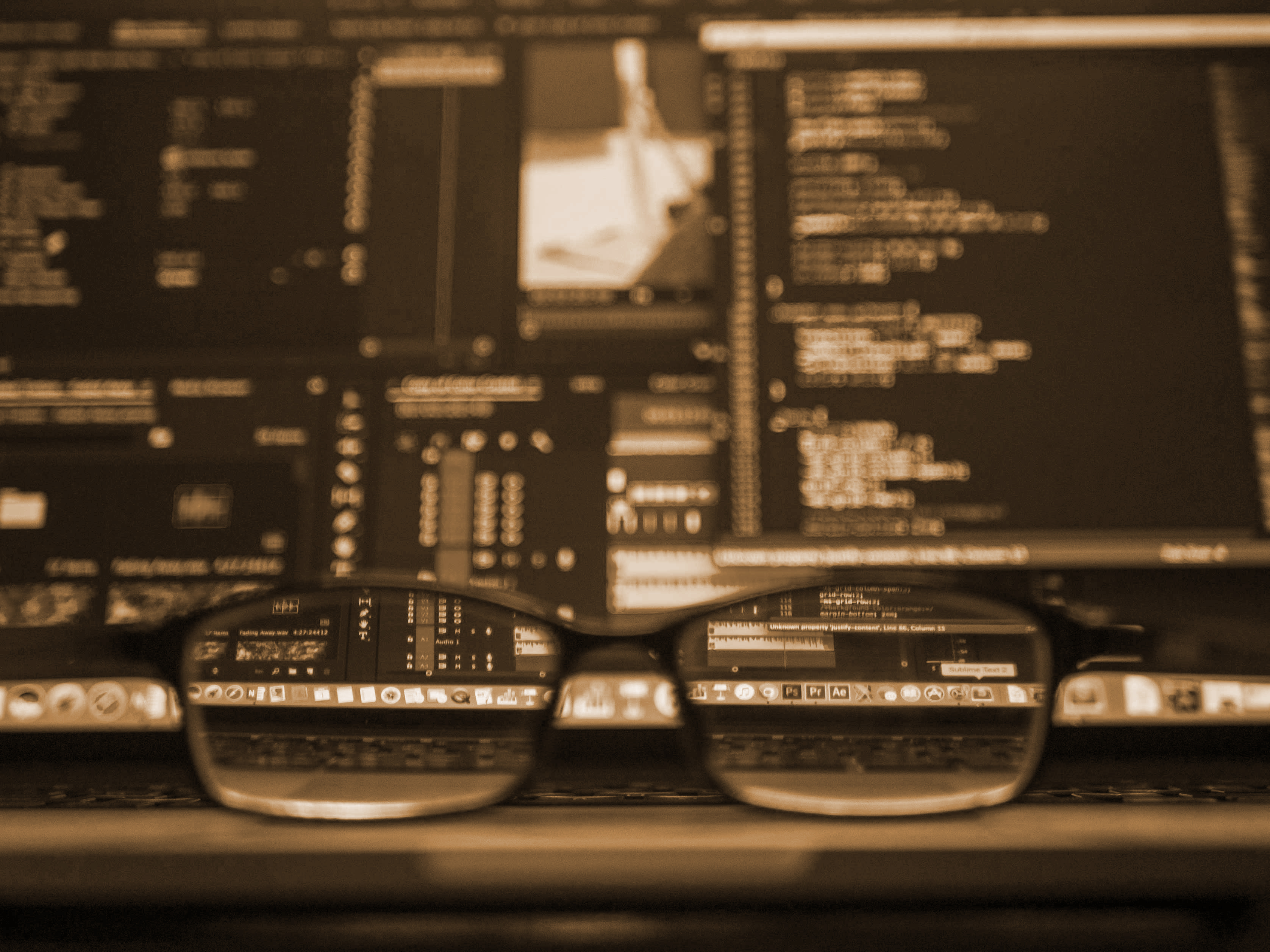 Close up view of code on a laptop, and glasses resting on the laptop keyboard